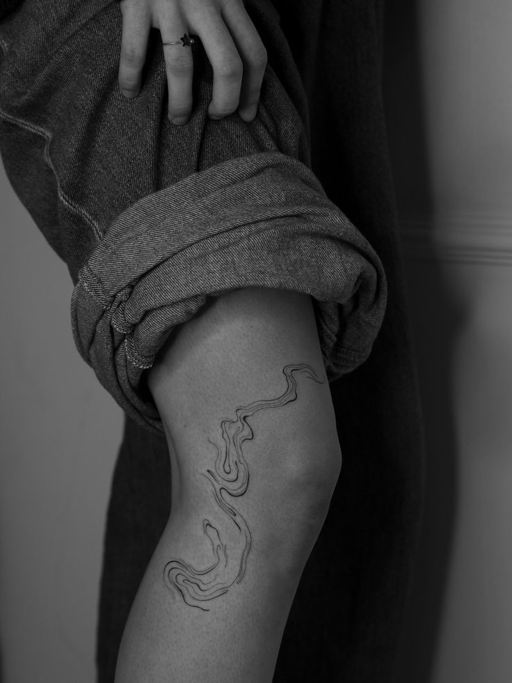 a person with a tattoo on their arm holding onto the leg of another person's leg