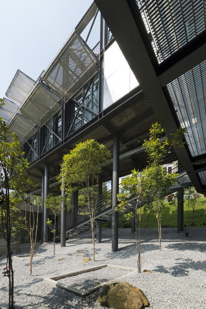 the building has many trees and rocks in front of it, as well as glass windows