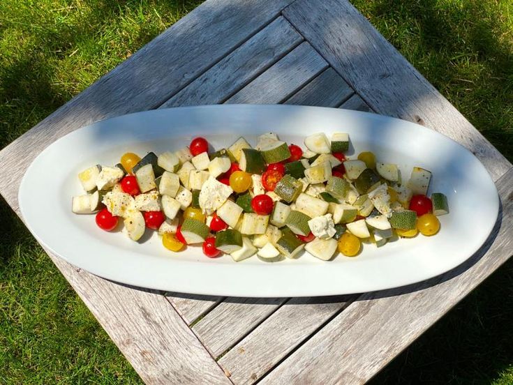 a white platter filled with assorted veggies on top of a wooden table