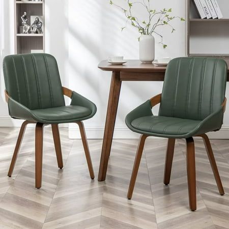 two green chairs sitting in front of a wooden table