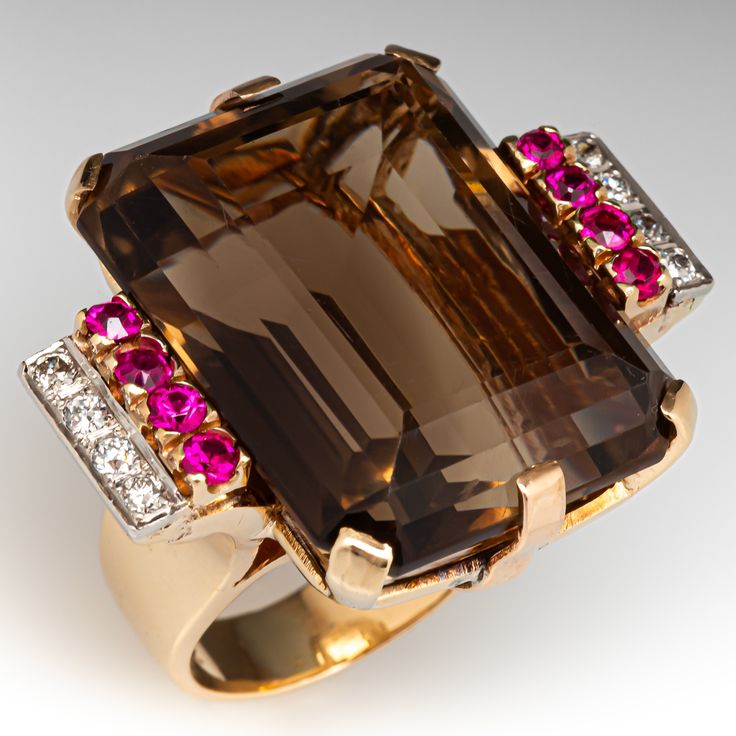 This retro circa 1940s ring is centered with one (1) emerald cut natural smoky quartz set into a six-prong setting. The shoulders of the ring are each accented with four (4) round transitional brilliant cut diamonds bead set into platinum and four (4) round single cut laboratory grown rubies set into yellow gold prong settings. The ring measures 26.5mm at the top, rises 13.8mm above the finger, tapering to 5.0mm wide and 1.2mm thick at the base of the shank. It is currently a size 6. 14k Gold Art Deco Rings With Cabochon, Art Deco 14k Gold Ring With Polished Finish, Vintage Cocktail Rings Art Deco, Vintage Ruby Rings, 1940s Ring, Antique Engagement Rings Sapphire, Estate Jewelry Rings, Ruby Ring Vintage, Luxury Gold Smoky Quartz Jewelry