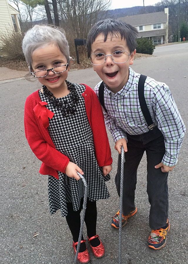 two young children standing next to each other on the street with an old fashioned cane