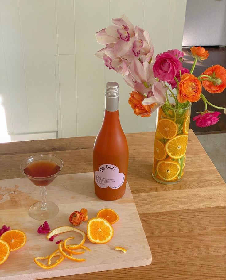 orange slices and flowers are on the table next to a wine bottle