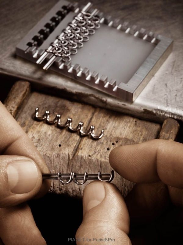 two hands are working on a piece of wood with metal hooks attached to the end