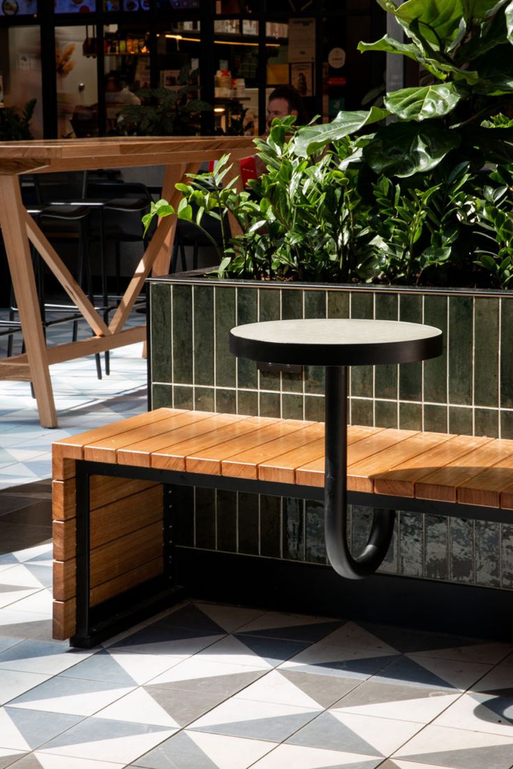 a wooden bench sitting next to a planter filled with flowers and potted plants