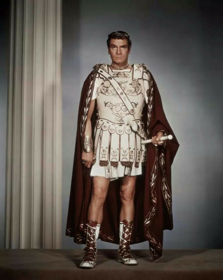 a man dressed in roman costume standing next to a column and wearing gladia boots