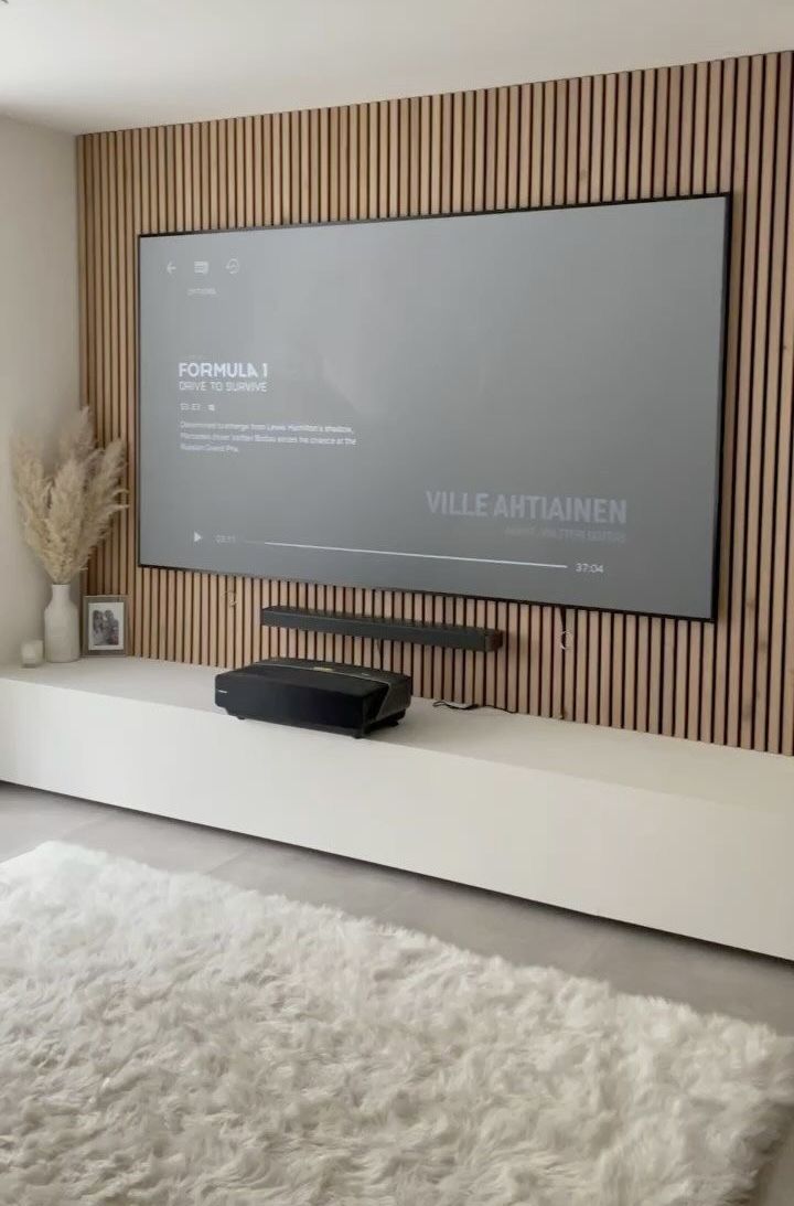 a flat screen tv sitting on top of a white shelf in front of a wall