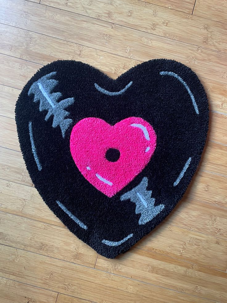 a black heart shaped rug with a pink heart on it