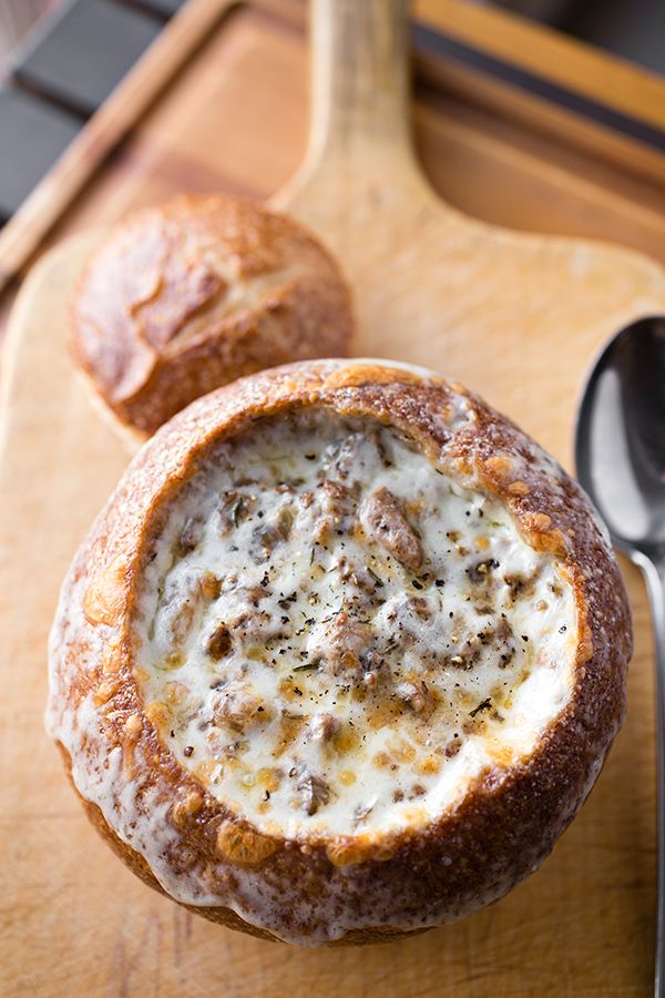 there is a bowl of soup on the table next to two loaves of bread