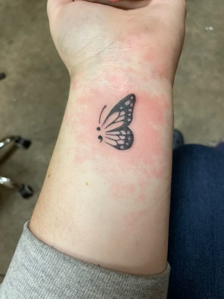 a woman's arm with a small butterfly tattoo on the left side of her wrist