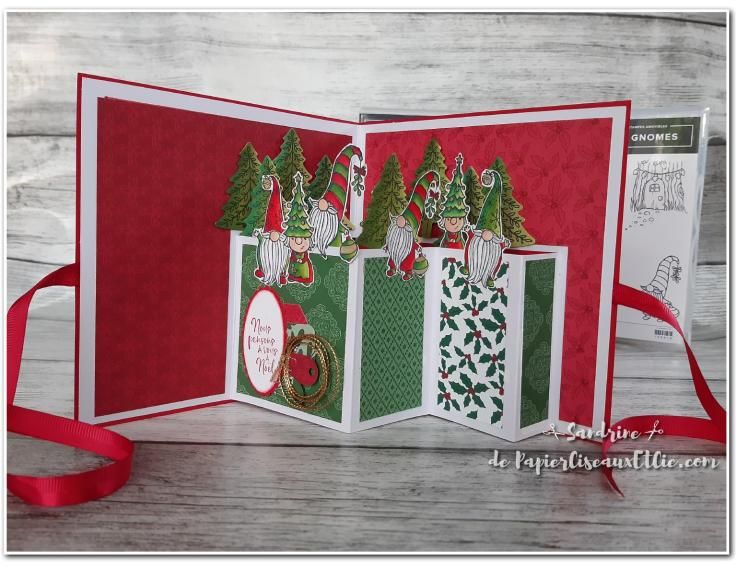 an open christmas card with red ribbon on the bottom and green trees in the middle