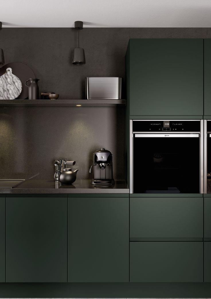 a kitchen with dark green cabinets and stainless steel appliances, including a built - in oven