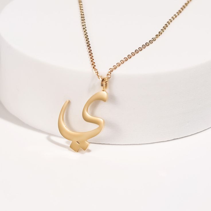 This stunning necklace features a beautifully crafted pendant with a personalized Arabic letter. The elegant design of the letter captures its unique and intricate beauty, making it a focal point of sophistication and charm. The pendant hangs from a delicate chain, perfect for adding a touch of elegance to any outfit. Ideal for everyday wear or special occasions, this necklace makes a meaningful and stylish statement. It also serves as a thoughtful and personalized gift for loved ones, celebrati Elegant Name Chain Necklace For Gift, Elegant Name Pendant Chain Necklace, Elegant Pendant Chain Necklace With Name, Initial Pendant Name Necklace With Adjustable Chain As Gift, Personalized Pendant Name Necklace, Name Pendant Necklace As A Gift For Her, Symbolic Initial Pendant Jewelry For Anniversary, Initial Pendant Charm Necklace As Gift For Her, Elegant Sterling Silver Nameplate Initial Necklace