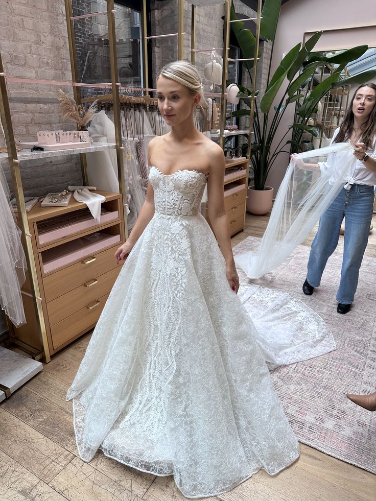 a woman in a white wedding dress standing next to a mannequin