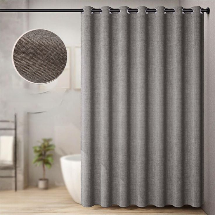 a gray shower curtain next to a white tub in a bathroom with a round mirror on the wall