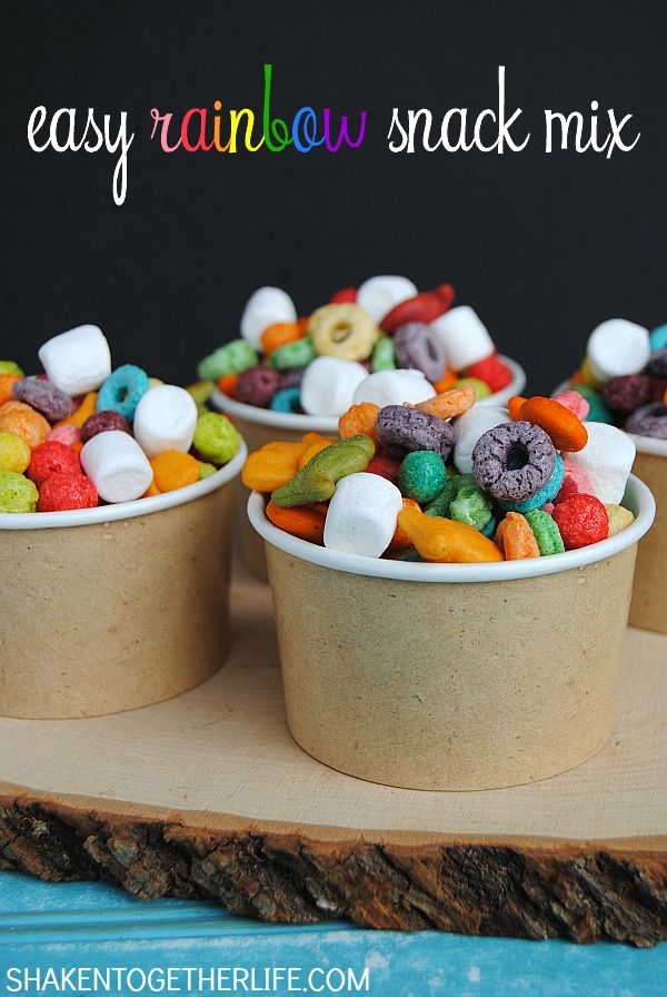 three small cups filled with colorful candy and marshmallows on a wooden tray