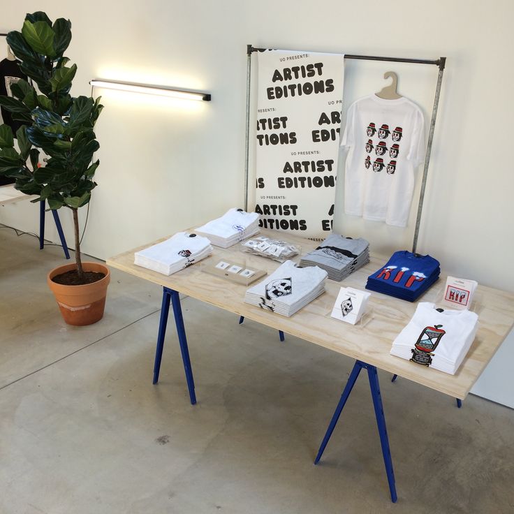 a table with various items on it next to a potted plant and an art exhibit sign