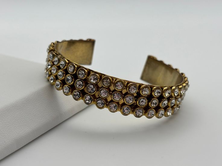 An incredible vintage shiny gold plated cuff!! Great vintage condition, with light patina to the gold plate throughout. All crystals are present. 5.7cm x 1.3cm. All jewellery is sanitised before posting.  -------------------- 🌟 P&P: 👉 Will arrive gift wrapped, in a gift box. 👉 UK shipping: Royal Mail Tracked 24 👉 International Shipping: Royal Mail International Tracked -------------------- 💎 FOLLOW US:  👉 www.instagram.com/janedreamsofvintage 👉 www.facebook.com/JaneDreamsOfVintage Gold Crystal Bracelet Costume Jewelry Gift, Vintage Gold Cuff Jewelry, Gold Jeweled Bangle For Anniversary, Vintage Jeweled Cuff Bracelet For Formal Occasions, Gold Jeweled Crystal Metal Bracelet, Gold Metal Crystal Bracelet With Bling, Gold Jeweled Cuff Bracelet As Gift, Gold Jeweled Cuff Bracelet For Gift, Gold Jeweled Cuff Bracelet For Gifting