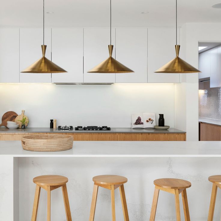 three wooden stools sit in front of a kitchen island with four pendant lights hanging over it