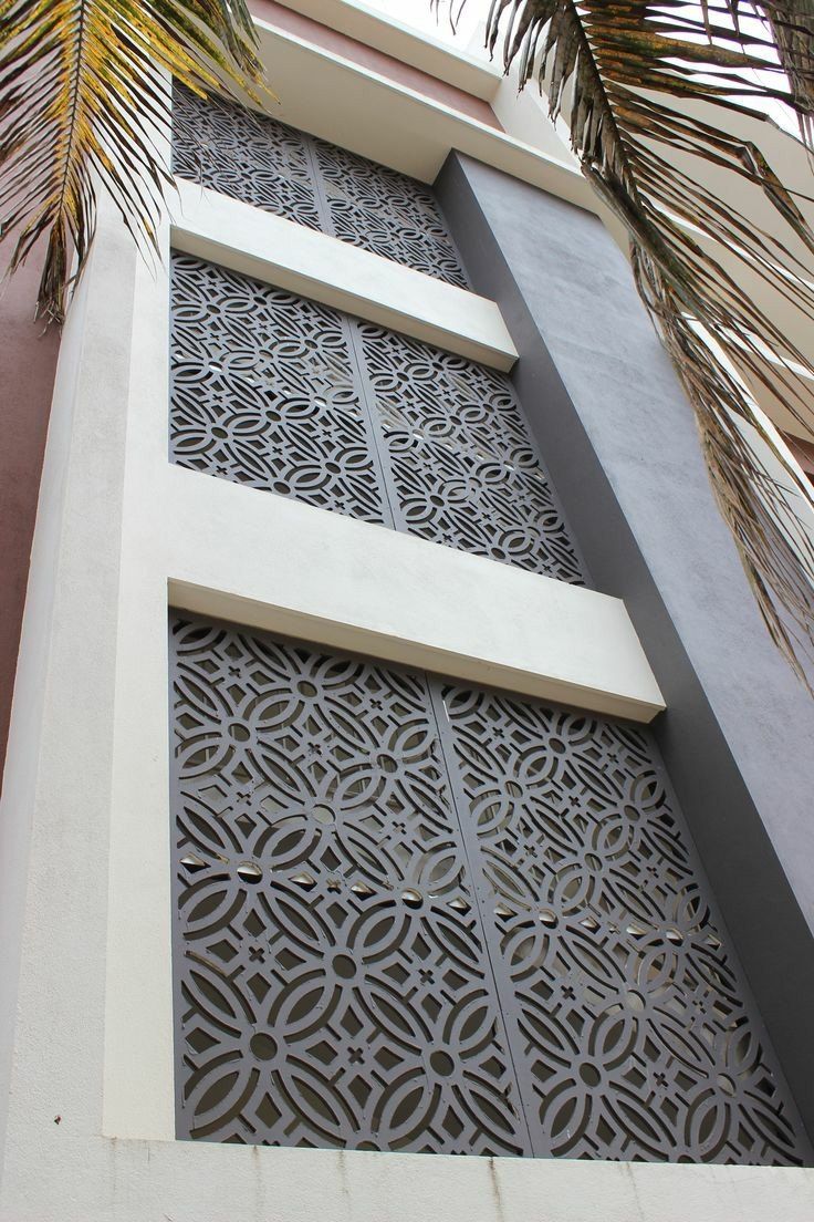 the side of a building with decorative ironwork on it's sides and palm trees in the foreground