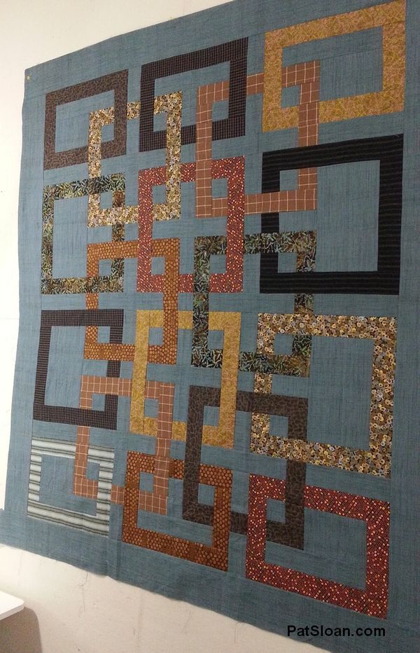 a wall hanging made up of squares and rectangles in blue, orange, yellow and brown