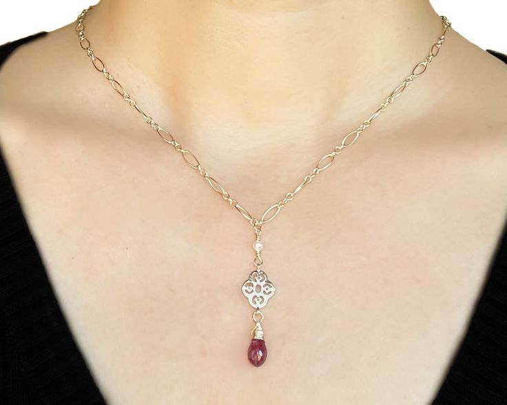 The ruby is probably the most well-known gemstone in the world, and its name will forever be linked with its striking red color. No other gemstone shares such a strong link with feelings of love and passion. Ruby is the birthstone for July and the gem for the 15th and 40th anniversaries. This necklace is in a classic style, incredibly elegant and refined. A ruby briolette stone dangles from a gold filigree; three tiny freshwater seed pearls are wire wrapped to the chain to add more dimension and Elegant Ruby Briolette Necklace, Elegant Ruby Birthstone Necklace In Gold, Elegant Gold Ruby Birthstone Necklace, Valentine's Day Ruby Birthstone Jewelry, Ruby Briolette Necklace In Fine Jewelry Style, Fine Jewelry Ruby Briolette Necklace, Ruby Briolette Fine Jewelry Necklace, Fine Jewelry Ruby Gift, Elegant Ruby Pendant Birthstone Necklace