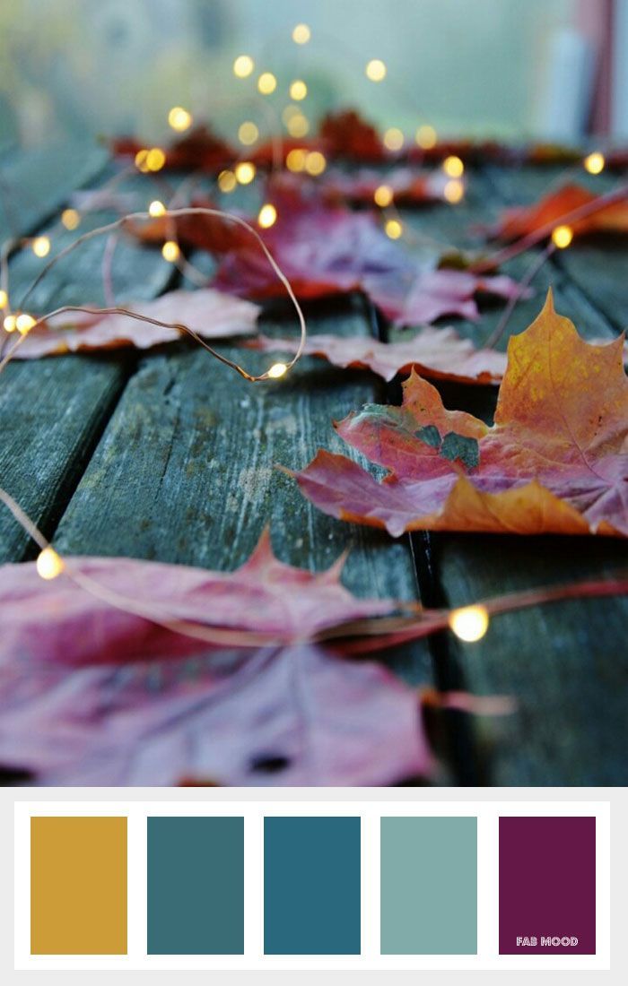 some leaves are laying on a wooden table with lights in the background and color swatches