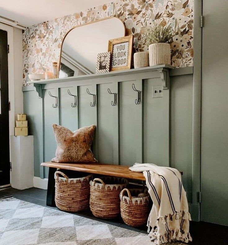 a wooden bench with baskets on it next to a wall mounted mirror and coat rack