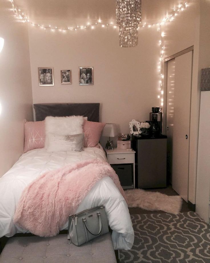 a bedroom decorated in pink and white with lights strung above the bed, luggage on the floor