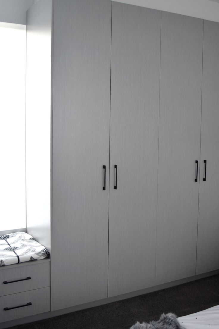 an empty bedroom with white cabinets and drawers