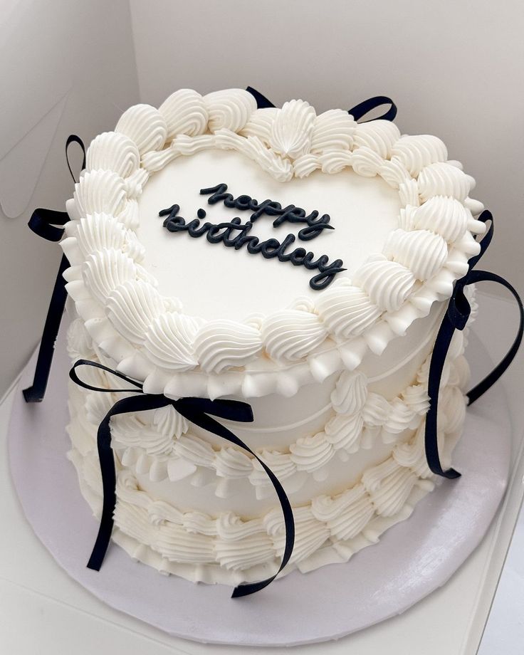 a heart shaped cake with the words happy birthday written on it in black and white icing