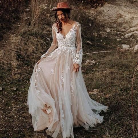 a woman in a dress and hat is walking through the grass