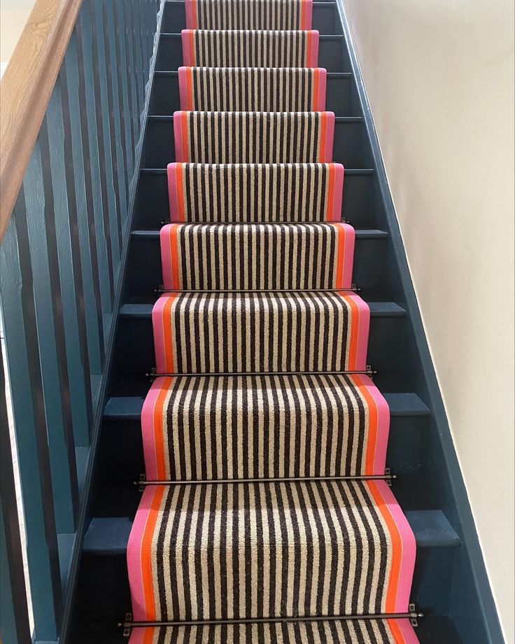 the stairs are lined with black and white striped carpet, along with pink and orange stripes