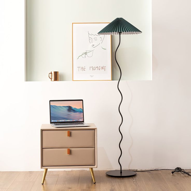 a laptop computer sitting on top of a dresser next to a lamp