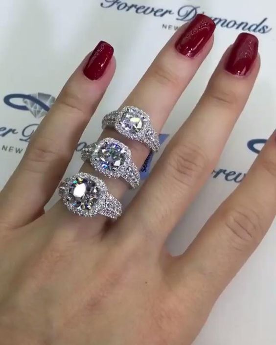 a woman's hand with three rings on it and two diamonds in the middle