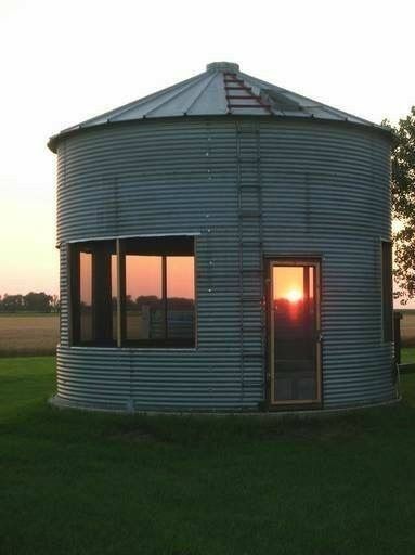 the sun is setting in front of a round building with windows on it's side