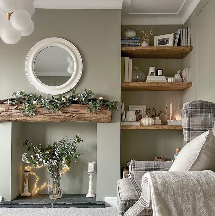 a living room filled with furniture and a fire place covered in greenery next to a mirror