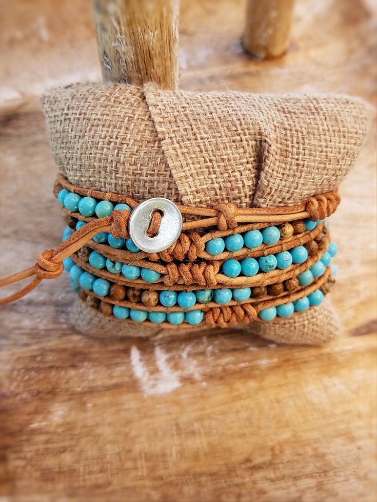 Chic boho wrap bracelet with Bright Turquoise colored beads mixed with Picture Jasper with decorative snake knot accents. Threaded onto natural color raw tan leather. Wraps around the wrist 5 times total. Bracelets are approximately 37 inches in length total and adjustable between 34-36 inches due to several loop closu Beaded Brown Wrap Bracelet For Beach, Beaded Brown Wrap Bracelet For The Beach, Adjustable Turquoise Wrap Bracelet For Festival, Brown Beaded Wrap Bracelet For Beach, Adjustable Natural Stone Wrap Bracelet For Festivals, Adjustable Hand Wrapped Bracelet For Festivals, Adjustable Hand Wrapped Wrap Bracelet For Festival, Festival Adjustable Hand Wrapped Bracelet, Bohemian Adjustable Hand Wrapped Bracelet