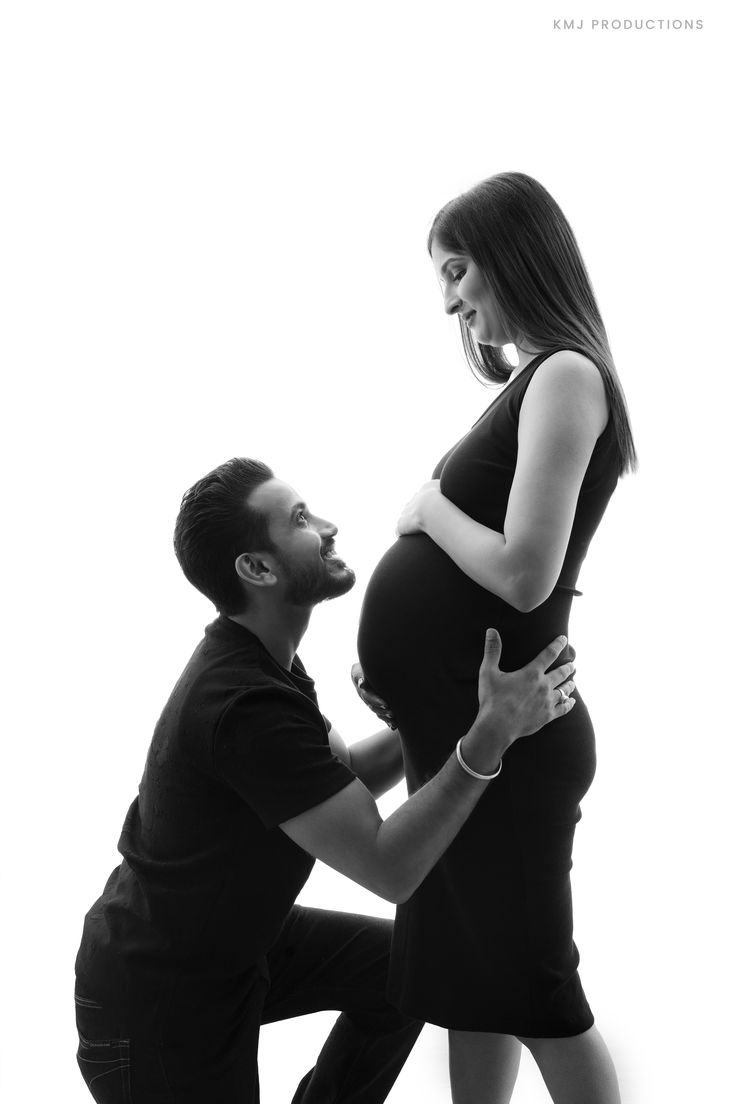 a man kneeling down next to a pregnant woman