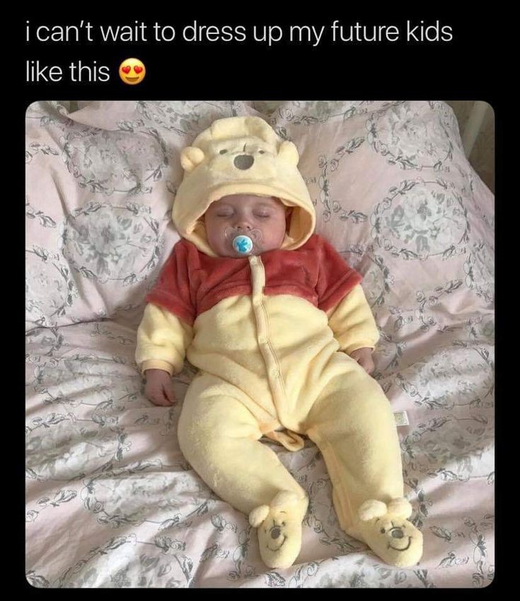 a baby in a winnie the pooh costume sleeping on a bed with a pacifier