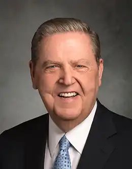 an older man in a suit and tie smiling for the camera while wearing a blue tie