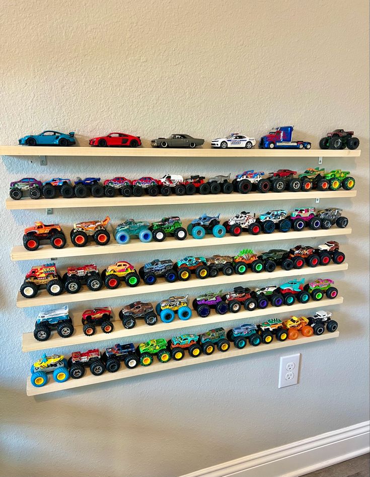 a wall mounted shelf filled with lots of different toy cars on top of white shelves