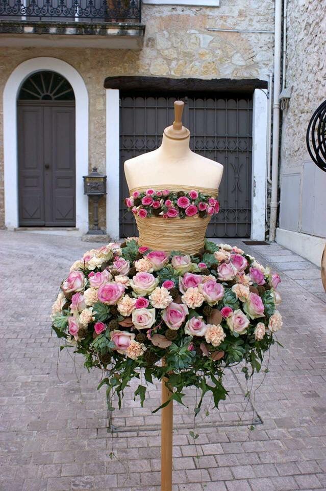 a mannequin is covered with flowers in front of a brick building on the street