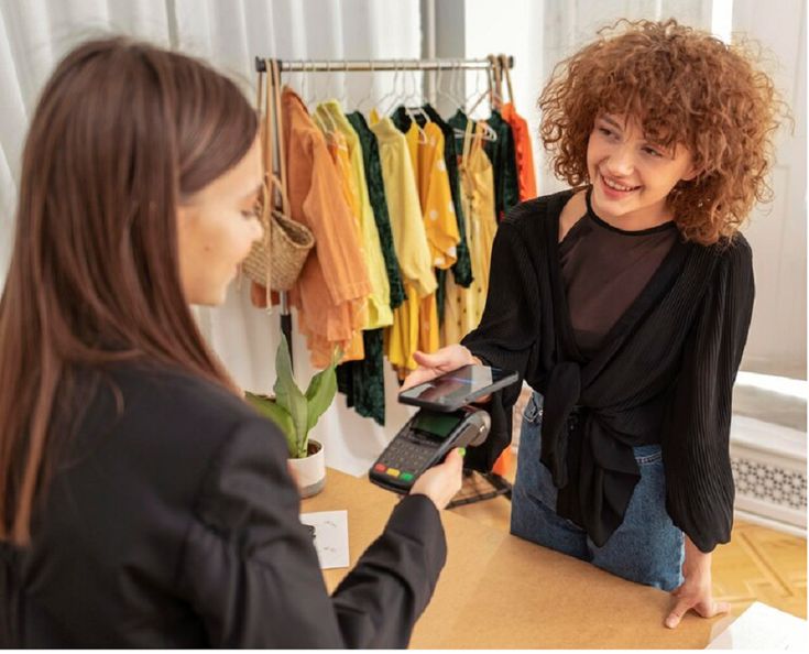 a woman standing in front of a counter with a cell phone and credit card reader