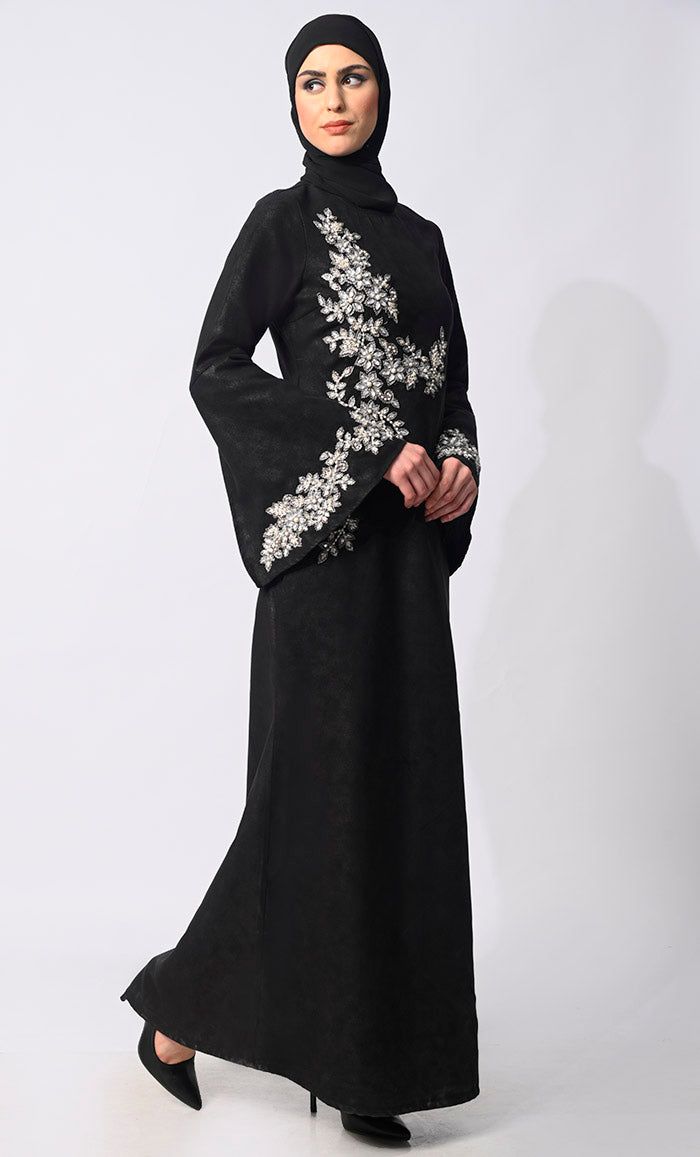 Step into the grace and charm of Eid celebrations with our exclusive Abaya Collection, featuring the epitome of elegance and sophistication. Our machine embroidered Abaya, meticulously adorned with pearl and stone handwork, is a testament to timeless beauty and exquisite craftsmanship. Crafted with meticulous attention to detail, this Abaya boasts delicate machine and Hand embroidery with stones and Pearls that adorns every inch, creating a mesmerizing tapestry of intricate patterns. Each stitch reflects a dedication to perfection, enhancing the allure of this traditional garment. The Abaya also features Round neck, flared sleeves , back zip closure and a loose belt for a cinched waist silhouette effect. Size & FitModel height is 5’9’ and is wearing a Small sizeMaterial & CareMaterial: Kor Elegant Maxi Dress For Eid, Elegant Formal Maxi Dress For Eid, Elegant Evening Maxi Dress For Eid, Fitted Black Abaya For Wedding, Black Abaya For Eid Party, Elegant Floor-length Abaya For Eid, Embroidered Long Sleeve Abaya For Party, Black Party Abaya For Eid, Elegant Fitted Abaya For Festive Occasions