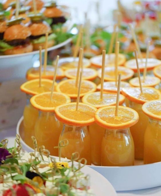 orange slices and strawberries are arranged on the trays with toothpicks in them