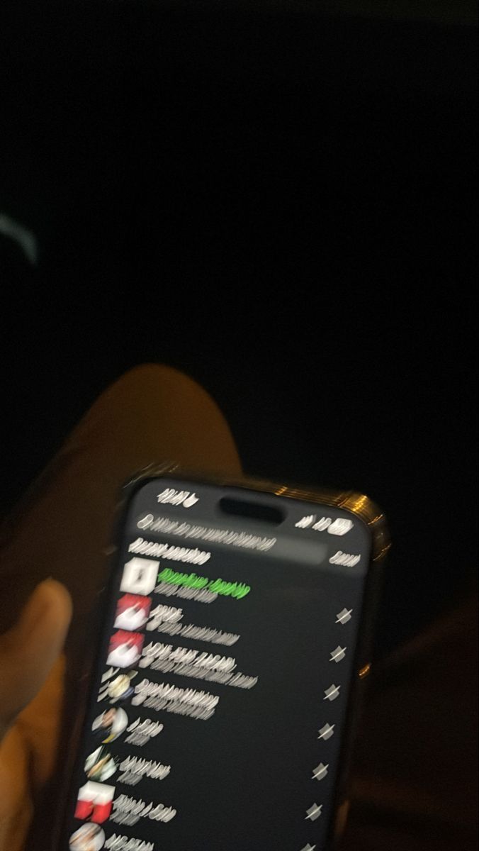 a person holding a cell phone in their hand with the screen lit up at night