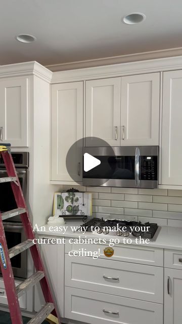 a kitchen with white cabinets and a red ladder in the middle that is being worked on