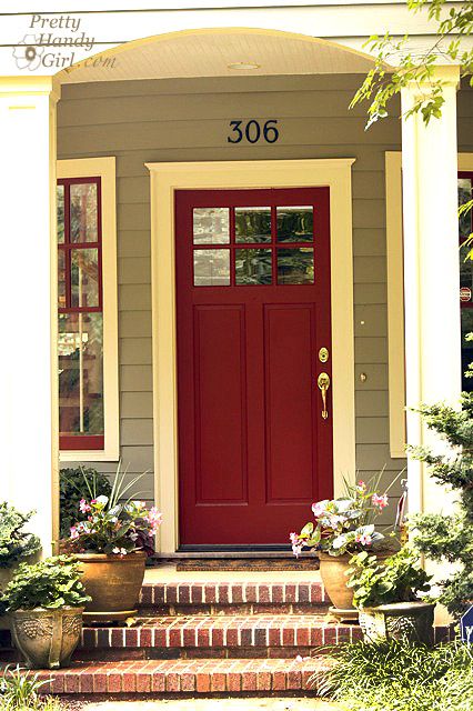 a red front door on a house with potted plants in the foreground and an advertizer below