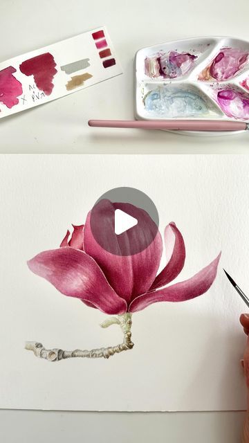 someone is painting a flower with watercolors on the paper and then using a brush